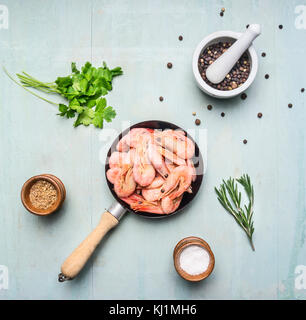 Cucina asiatica ingredienti freschi con piccoli gamberi in una piccola padella, erbe aromatiche e pepe su legno sfondo blu vista superiore Foto Stock