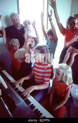 Famiglia riunita attorno al pianoforte Foto Stock