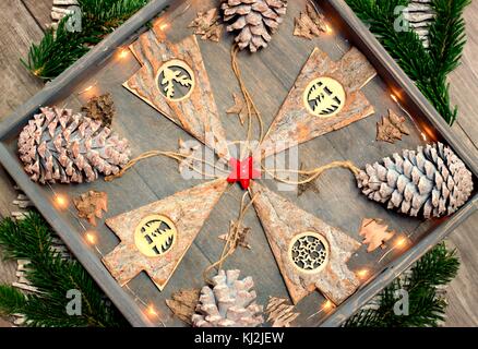 Sfondo dalla decorazione di natale, modello e disegno concetto-albero di natale fatto di legno, coni e lampadine su un vassoio di legno Foto Stock