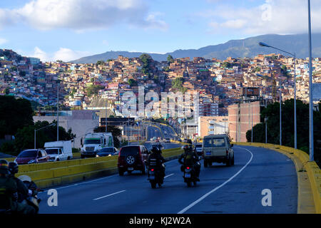 Venezuela, Santiago de Leon de Caracas: Guzmán‡n Blanco bidonville in città alta e membri della guardia nazionale andare in motocicletta sulla strada Foto Stock