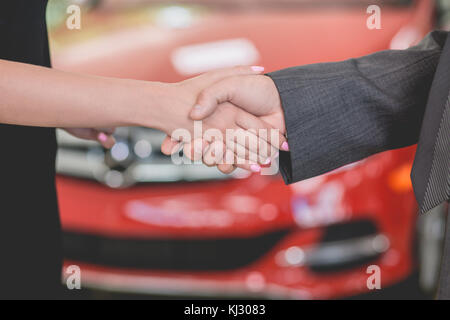 Concessionario veicolo agitando la mano con la giovane donna. Foto Stock