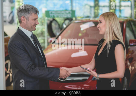 Felice giovane femmina aveva di scuotimento con il rivenditore di auto. Foto Stock