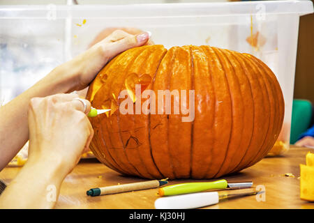 Close up le mani delle donne che tagli jack-o-lantern con coltello. Zucca di Halloween. vacanze simbolo. Foto Stock
