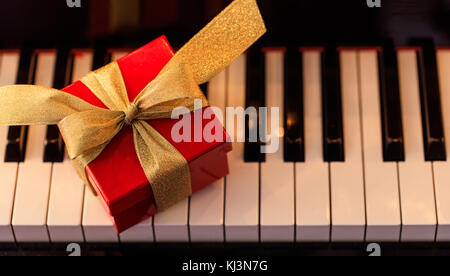 Confezione regalo rossa su di una classica tastiera di pianoforte, sopra visualizza Foto Stock
