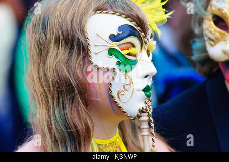 Interprete femminile che indossa una maschera di porcellana nel carnevale del edinburgh jazz e blues festival che si muove in basso lungo il tumulo verso Princes street Foto Stock