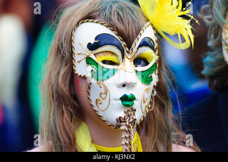 Interprete femminile che indossa una maschera di porcellana nel carnevale del edinburgh jazz e blues festival che si muove in basso lungo il tumulo verso Princes street Foto Stock