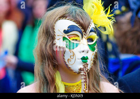 Interprete femminile che indossa una maschera di porcellana nel carnevale del edinburgh jazz e blues festival che si muove in basso lungo il tumulo verso Princes street Foto Stock