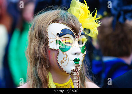 Interprete femminile che indossa una maschera di porcellana nel carnevale del edinburgh jazz e blues festival che si muove in basso lungo il tumulo verso Princes street Foto Stock