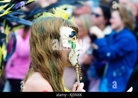 Interprete femminile che indossa una maschera di porcellana nel carnevale del edinburgh jazz e blues festival che si muove in basso lungo il tumulo verso Princes street Foto Stock