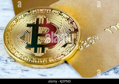 La moneta in oro bitcoin si trova sulla Gold carta bancaria. macro con blur Foto Stock