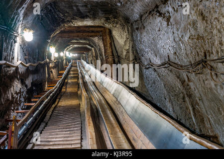 Belt conveyot in illuminated underground tunnel in salt mine Foto Stock