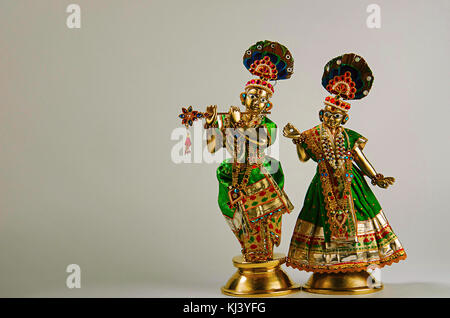 Statua in ottone di Lord Krishna con flauto e Radha (figura intera) con mukut o corona su sfondo grigio chiaro Foto Stock