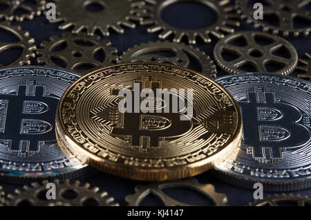 Tre bitcoins tra i vari ingranaggi extreme closeup su sfondo sfocato. cryptocurrency concetto. Foto Stock
