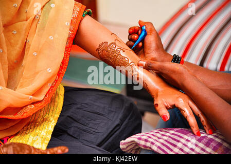 Artista Mehndi (Henna Tattoos) che disegna mehndi sulla mano sinistra di una signora in un evento culturale, Pune, Maharashtra, India Foto Stock