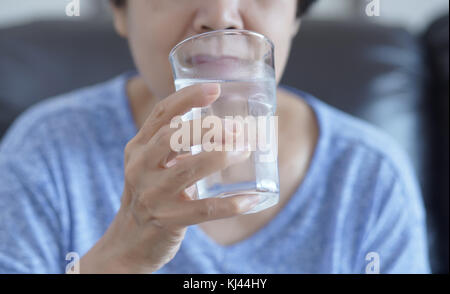 Ritratto di donna anziana di bere un bicchiere di acqua per il pensionamento in home Foto Stock