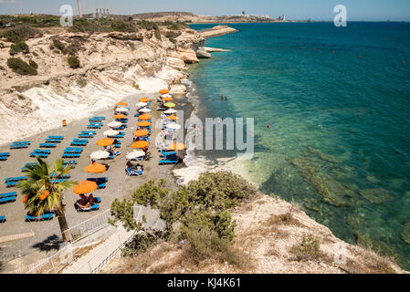 Un piccolo kalymnos Beach con un paio di sedie a sdraio e ombrelloni, tra larnaca e limassol, Cipro Foto Stock