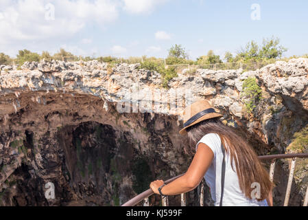 Donna non identificata che guarda la fossa dell'inferno (cehennnem) situata nel distretto di Silifke, Mersin Turchia. Foto Stock