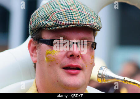 Musicista maschio con gli occhiali e un tappo piatto a giocare il sousaphone nel carnevale del edinburgh jazz e blues festival Foto Stock