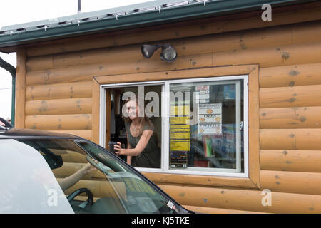 Kodiak, Alaska, Stati Uniti d'America - 8 agosto 2017: una giovane donna barista serve un cliente a isola di caffè espresso shop collocato in mill bay road, Kodiak, Foto Stock