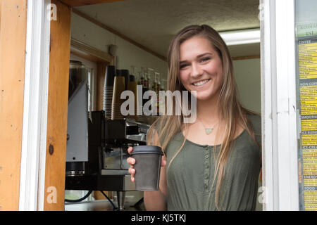 Kodiak, Alaska, Stati Uniti d'America - 8 agosto 2017: una femmina barista sta tenendo in mano un bicchiere di carta con caffè a isola di caffè espresso shop collocato in mill bay road, k Foto Stock