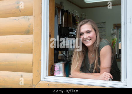 Kodiak, Alaska, Stati Uniti d'America - 8 agosto 2017: una femmina barista è in posa per una foto sulla finestra dell'isola espresso coffee shop, Kodiak, Alaska. Foto Stock