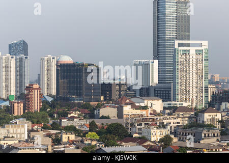 Vista aerea di un basso edificio residenziale in contrasto con un moderno condominio e torri di uffici nel cuore di Jakarta, Indonesia città capitale. Foto Stock