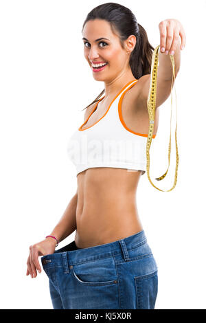 Donna con jeans di grandi dimensioni nel concetto di dieta tenendo un nastro di misurazione Foto Stock