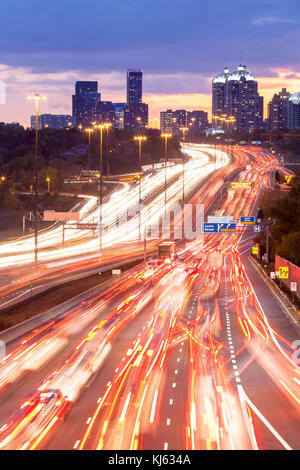 Auto lasciando sentieri di luce durante una lunga esposizione lungo il Re della strada statale 401 a notte a Toronto, Ontario, Canada. Foto Stock