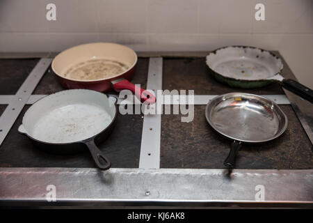 Quattro vecchi padelle su una vecchia piastra industriale. La povertà Foto Stock