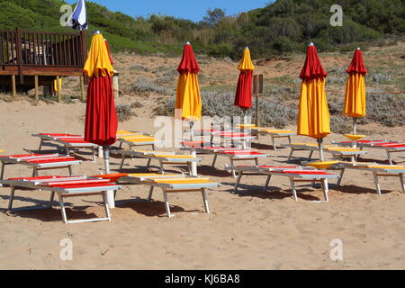 Chiuso ombrelloni e lettini su una spiaggia deserta fuori stagione. Foto Stock