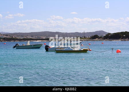 Piccole barche da pesca ancoraggio in una baia con acqua sarda. Foto Stock