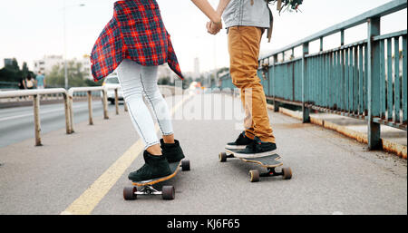 Giovane coppia attraente skateboard equitazione e divertimento Foto Stock