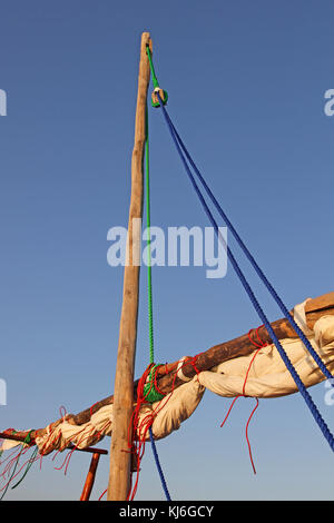 Barca montante riderhow con vela verso il basso e legato in su contro il cielo blu, Zanzibar, isola di Unguja, Tanzania. Foto Stock