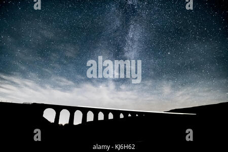 Una lunga esposizione di un treno che passa oltre il viadotto Ribblehead, mentre l'incredibile Via Lattea aumenta al di sopra di Foto Stock