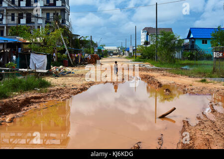 Un giovane ragazzo camminando per le strade di rotte in Sihanoukville. la Cambogia sta avendo una ripresa economica ma ci sono persone con meno di un dollaro al giorno. Foto Stock