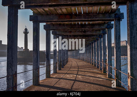 Travi di legno intemperie sotto il molo del porto occidentale a Whitby, North Yorkshire, in un giorno luminoso autumns nel mese di ottobre. Foto Stock