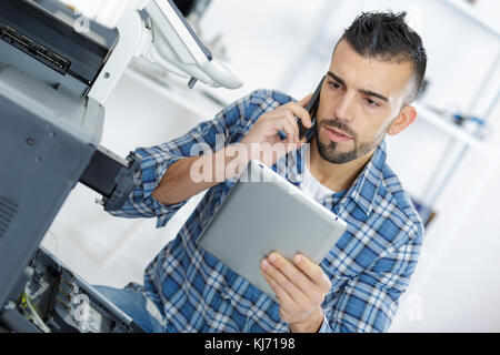 Tecnico utilizzando il suo telefono portatile e tablet Foto Stock