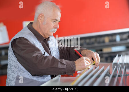 Meccanico senior di lavorare sulla macchina in fabbrica Foto Stock