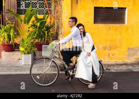 Giovane coppia appena sposata in bicicletta nel centro storico di Hoi An, Vietnam, Asia, patrimonio dell'umanità dell'UNESCO Foto Stock