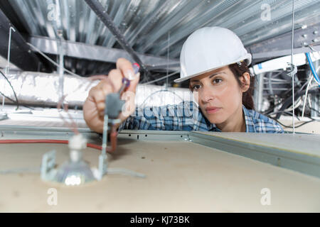 Elettricista femmina lavorando su spotlamp dal di sopra Foto Stock