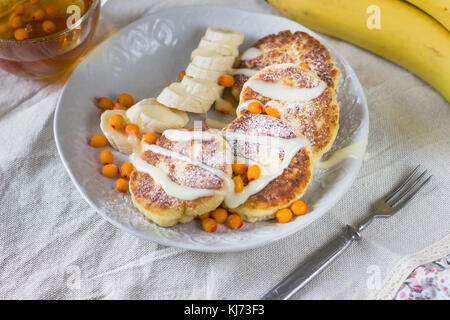 Cottage cheese pancakes con fettine di banana e mare backthorn bacche. una sana prima colazione Foto Stock