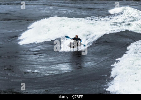 Un uomo helmeted kayak di una faccia di un enorme ondata di Sechelt Rapids, una delle più veloci del mondo passa di marea (Skookumchuck si restringe, British Columbia). Foto Stock