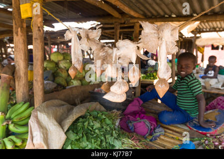 Sacchetti di arrow-polvere sul display alla frutta e verdura in stallo un mercato con ragazzo sullo sfondo l'ombra, Uganda, Africa Foto Stock