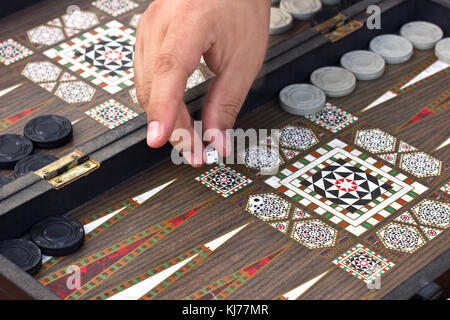 Una mano d'uomo detiene un backgammon Foto Stock