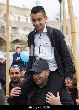 Ragazzo adolescente sulle spalle di suo padre a bar mitzvà celebrazione, Safed, distretto settentrionale, Israele Foto Stock