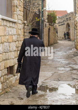 Vista posteriore del uomo a camminare nella strada bagnata, Safed, Distretto Settentrionale, Israele Foto Stock