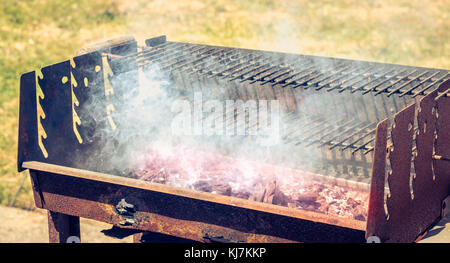 Vecchio arrugginito barbecue per la cottura a vapore quando l'illuminazione in un giardino Foto Stock