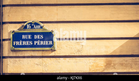 Blue strada parigina segno su un muro di pietra dove è scritto in francese - sedicesimo arrondissement rue perier fratelli Foto Stock