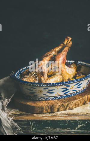 Arrosto di pollo intero per la vigilia di Natale celebrazione su tavola in legno rustico, scheda muro nero sfondo, spazio di copia Foto Stock