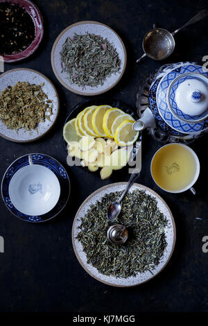 Foglie di tè diverse con fette di limone su sfondo scuro Foto Stock